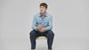 Modelo con camisa de jean celeste y jean azul oscuro sentado en un banco, campaña Jack & Jones